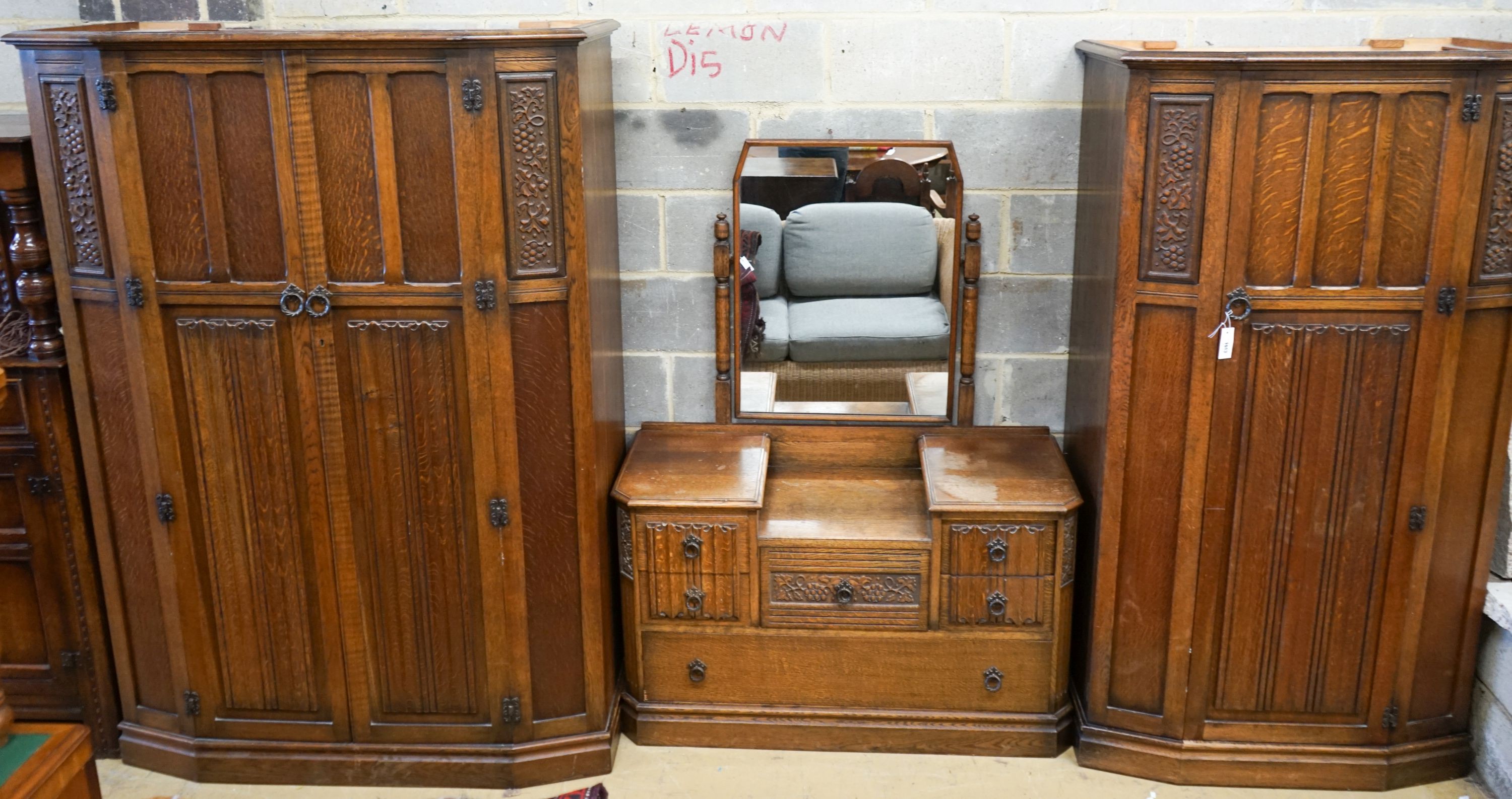 An early 20th century Jacobean revival linenfold moulded oak three piece bedroom suite, larger wardrobe length 128cm, depth 58cm, height 183cm